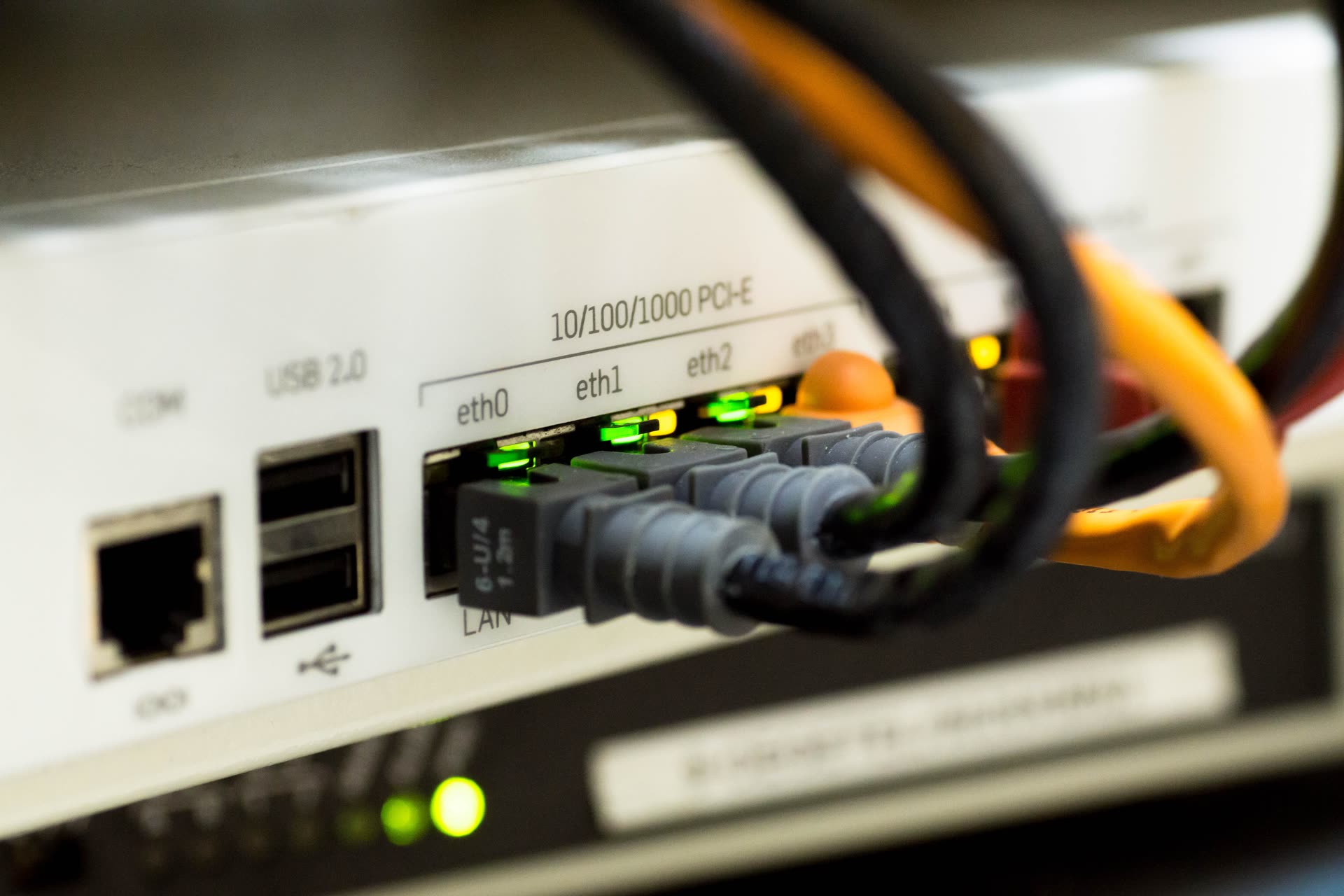 Network cables plugged into the Ethernet ports of a small network appliance.